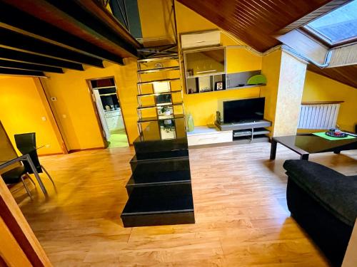 sala de estar con escaleras y paredes amarillas en Buhardilla original, en León