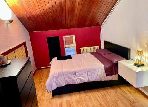 1 dormitorio con cama y pared roja en Buhardilla original, en León