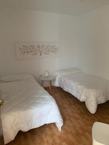 2 camas en una habitación blanca con mesa en Apartahotel Playa Conil, en Conil de la Frontera