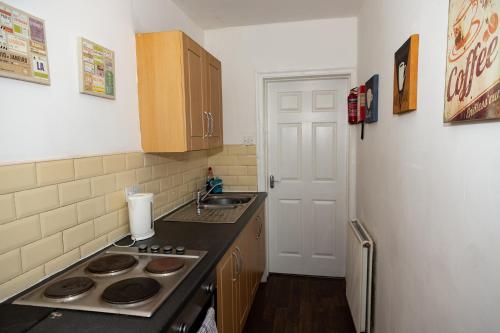 a small kitchen with a stove and a sink at Alexander Apartments Rooms 2 in South Shields