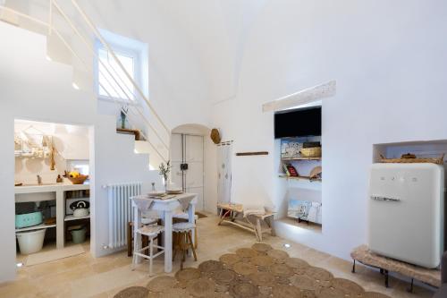 a kitchen with a table and a white refrigerator at BELLE HOME OSTUNI vasca vista mare in Ostuni