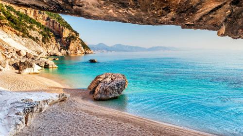 a rock in the water on a beach at Le Corti Sarde Apartments in Bari Sardo