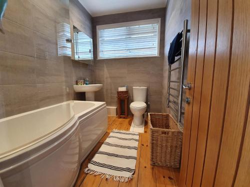 a bathroom with a tub and a toilet and a sink at Hoblyns Cove in Holywell Bay