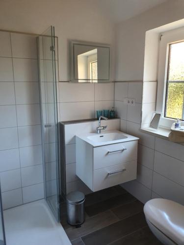 ein weißes Bad mit einem Waschbecken und einer Dusche in der Unterkunft Olle Kolle in Wremen