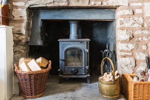a stove in a brick fireplace with two baskets at The Wee Cottage in Drumnadrochit