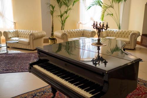 a piano in a living room with couches at Hotel Parco delle Fontane in Siracusa