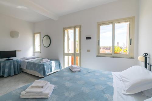 a white room with two beds and a window at Hotel Villino Gallodoro in Taormina