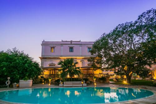 a building with a swimming pool in front of a building at Hotel Parco delle Fontane in Siracusa