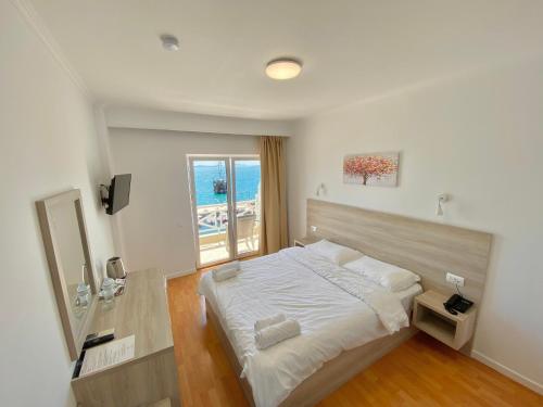 a bedroom with a large bed and a window at Sun N Blue Hotel in Sarandë
