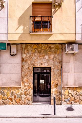 ein Steingebäude mit einer Tür und einem Balkon in der Unterkunft Coqueto Alojamiento in Martos