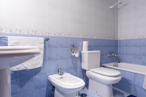 a blue tiled bathroom with a toilet and a sink at Coqueto Alojamiento in Martos