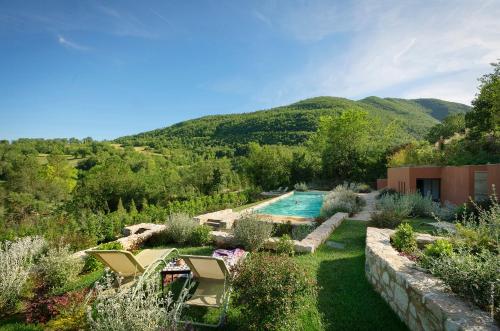 un jardin avec une piscine et des montagnes en arrière-plan dans l'établissement Castello Di Postignano Relais, à Sellano