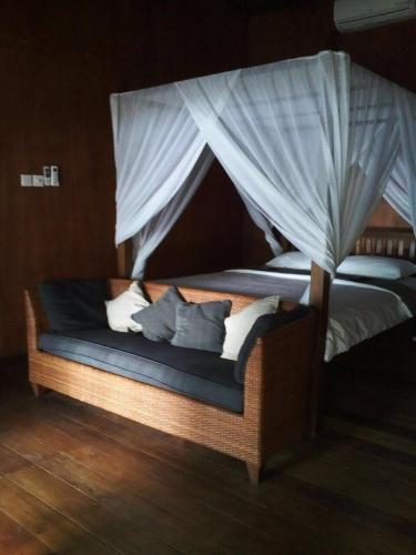 a bed with a canopy with pillows on it at The BeachHouse Tanjung Lesung in Cipakus