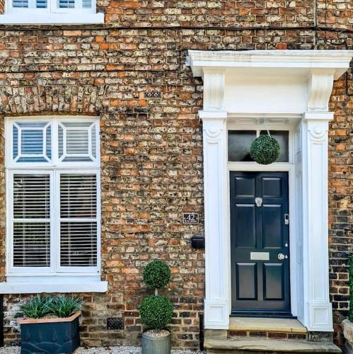 a brick house with a black door and two windows at 42 is the Answer- Stunning York townhouse appearing on TV Holiday Home Show in York