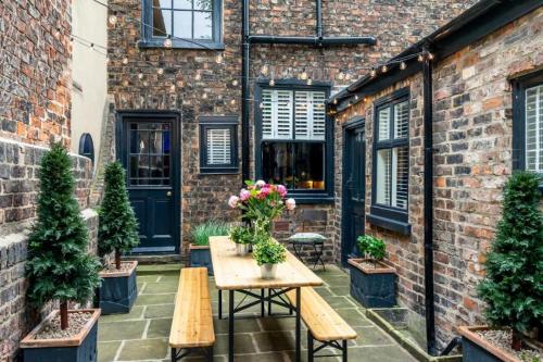 a patio with a table and benches and a brick building at 42 is the Answer- Stunning York townhouse appearing on TV Holiday Home Show in York