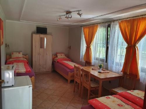 a room with two beds and a table and a kitchen at Strand Apartmanok in Bogács