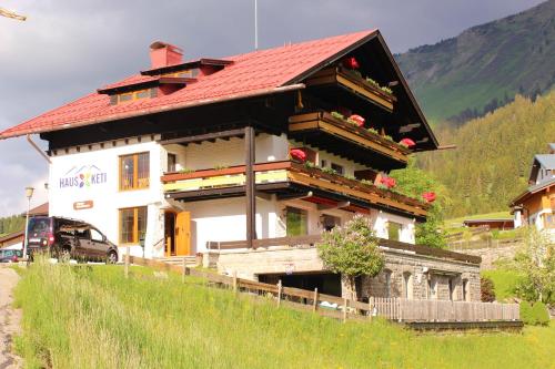 une maison avec un toit rouge sur une colline dans l'établissement Haus Keti, à Riezlern