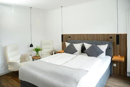 a bedroom with a large white bed and a chair at Am Rosenhain 14 Am Rosenhain 14 Appartement 3 in Timmendorfer Strand