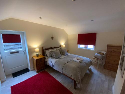 a bedroom with a large bed and a red rug at Deeside Snugs Apartments in Kincardine OʼNeil