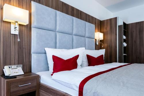 1 dormitorio con 1 cama grande con almohadas rojas en STEIGER Hotel Rathener Hof en Kurort Rathen