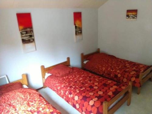 - 2 lits dans une chambre avec des draps rouges dans l'établissement DOMAINE DE KERIVIN, à Dirinon