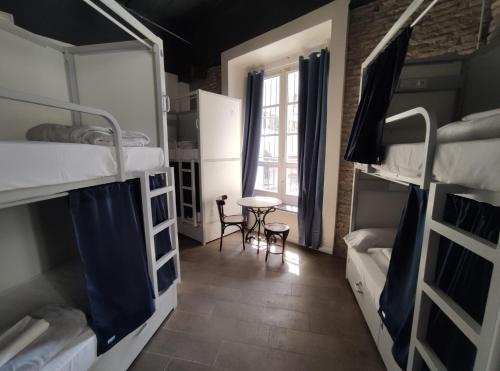 pokój z dwoma łóżkami piętrowymi i stołem w obiekcie Black Swan Hostel Sevilla w Sewilli