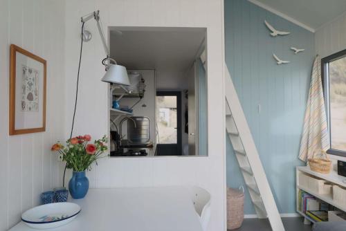 ein Badezimmer mit einem Spiegel und einem Tisch mit Blumen in der Unterkunft Slaapstrandhuisje - Strand dishoek 60 Dishoek in Vlissingen