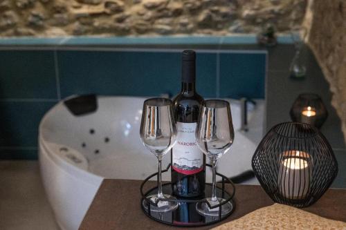 a bottle of wine and two wine glasses on a table at A 20 Passi... in Rocca Imperiale