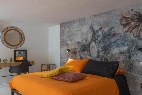 1 dormitorio con 1 cama de color naranja y una pintura en la pared en A 20 Passi... en Rocca Imperiale