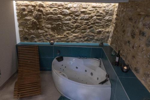 y baño con bañera y pared de piedra. en A 20 Passi..., en Rocca Imperiale