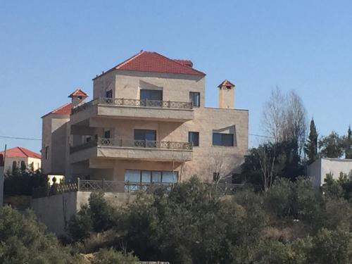 a building on a hill with trees in front of it at Charming House in Amman + Balcony in Amman