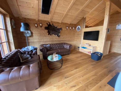 a living room with leather couches and a television at Jagdhütte in Lachtal