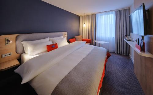Holiday Inn Express Cologne Mülheim, an IHG Hotel في كولونيا: سرير أبيض كبير في غرفة الفندق