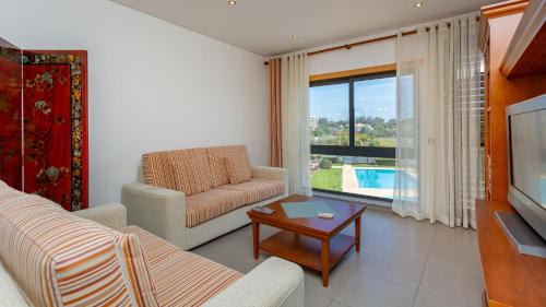 a living room with a couch and a tv at Parque Atlântico Apartment T1 in Quarteira