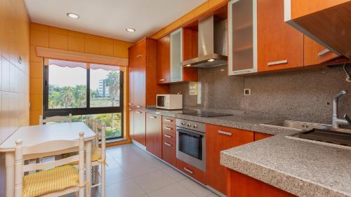 a kitchen with wooden cabinets and a counter top at Parque Atlântico Apartment T1 in Quarteira