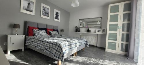 a bedroom with a bed with a checkered blanket and a mirror at Apartamenty Aquarius - Formoza in Gdynia