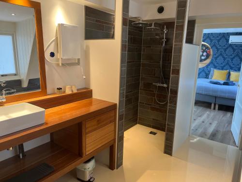a bathroom with a sink and a shower with a mirror at B&B Bommelsteijn in Dordrecht