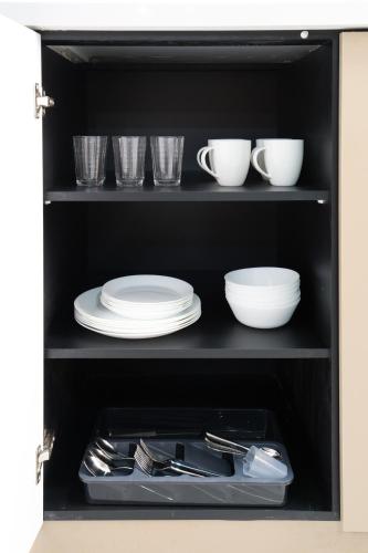 a black cabinet with plates and cups and utensils at ROMSUITES - Apartment with jacuzzi & pool table, Haifa center, Bahai Garden in Haifa