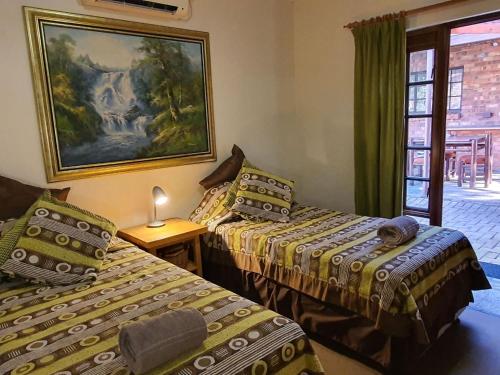 two beds in a room with a picture on the wall at Tamboti House in Malelane