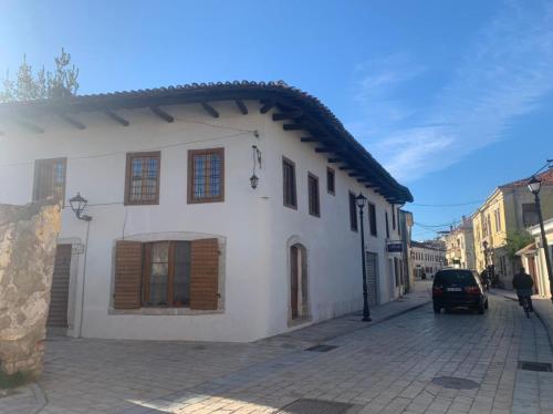 a white building with wooden windows on a street at Rooms for Rent in Shkodër