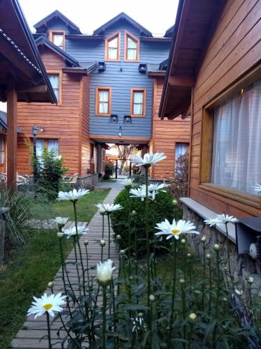 a garden with white flowers in front of a house at Cabañas Aitue in San Martín de los Andes