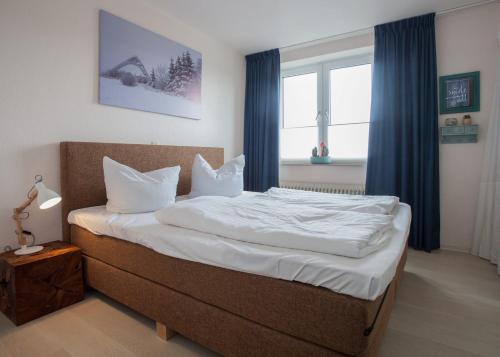 um quarto com uma cama com lençóis brancos e cortinas azuis em Appartement - Weltringpark 2-D Winterberg em Winterberg