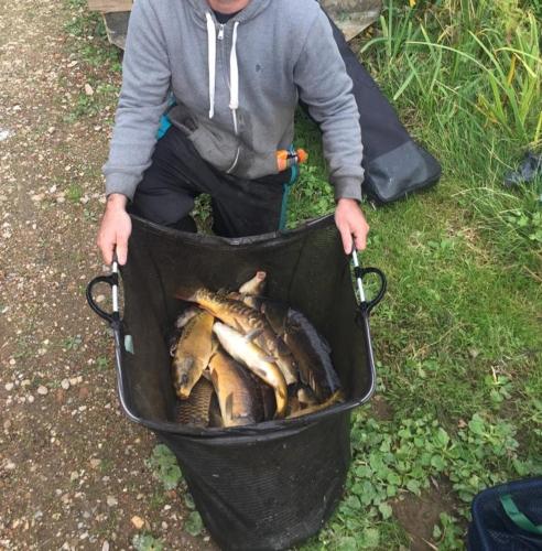 a man is holding a basket of fish at Peacock Lake Glamping in Nottingham