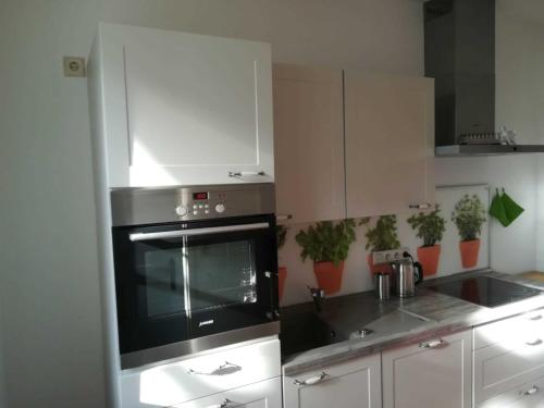 eine Küche mit einem schwarzen Backofen und weißen Schränken in der Unterkunft Ferienwohnung am Kirchplatz 25561 in Weener