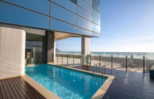 a house with a swimming pool next to the beach at Sea and Mountain View Paradise Designer 2 Bedroom Apartment 4 Adults and 2 Kids ONLY - Minimum 3 night stay - in STRAND - With Back-up power! in Cape Town