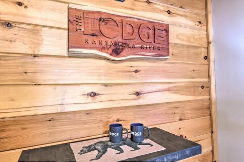 a sign on a wooden wall with two mugs on a table at The Lodge Nantahala River in Bryson City