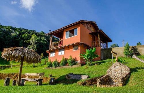 a house sitting on top of a lush green field at Pousada Barra Das Antas in Visconde De Maua