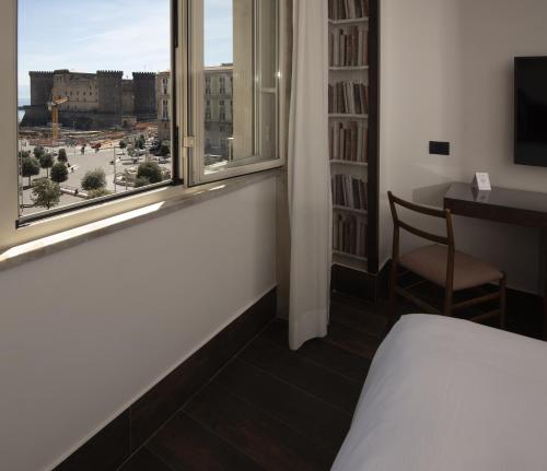 a bedroom with a bed and a window and a chair at Domus Vista Castello in Naples