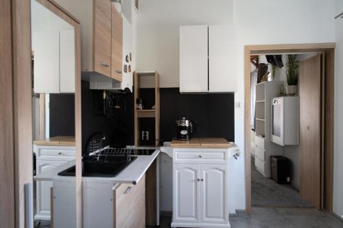 una cocina blanca con armarios blancos y fregadero en Stylowy apartament w historycznej części Gdańska, en Gdansk