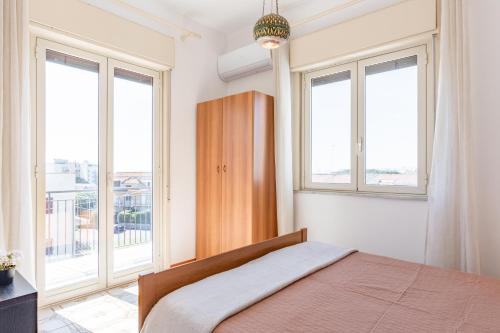 a bedroom with a bed and two windows at Giardini Naxos Apartment with Terrace near the Sea in Giardini Naxos